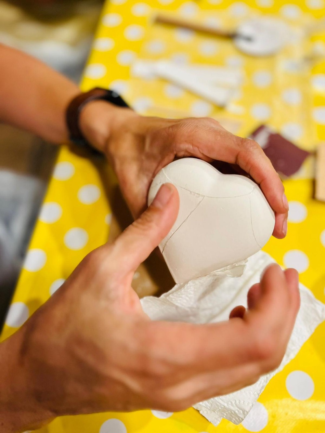 Mani che ricompongono un cuore di ceramica